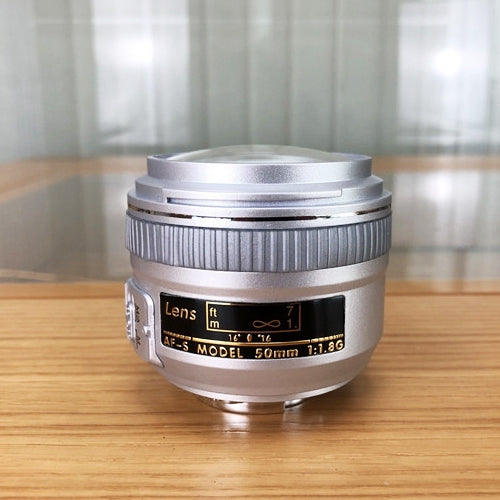 Silver fake camera lens model with engraved markings and metal mount base