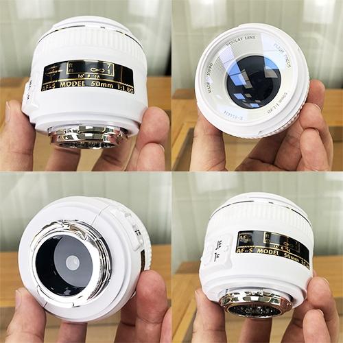 White fake camera lens model held in hand, front and back views
