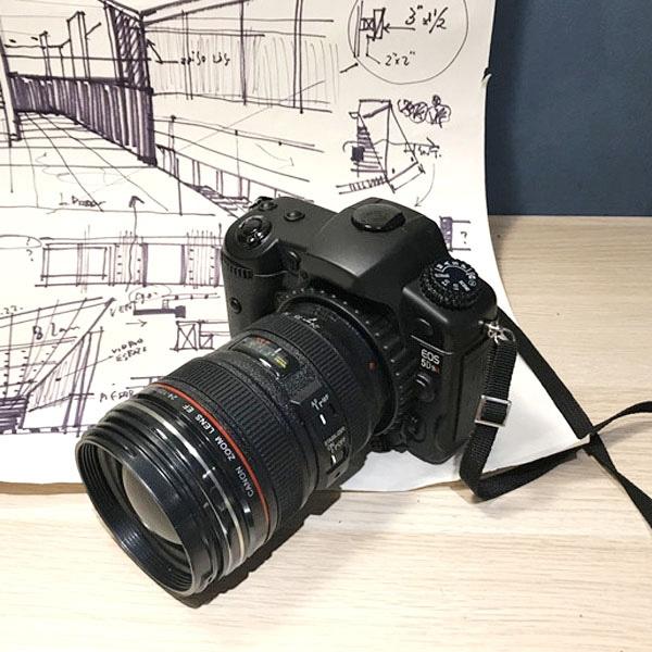 Black dummy DSLR camera prop angled view with attached lens and neck strap