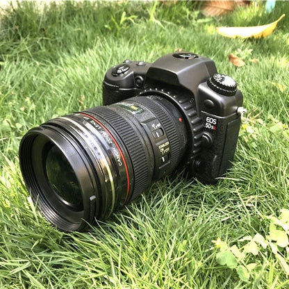 Black dummy DSLR camera prop on grass with attached zoom lens