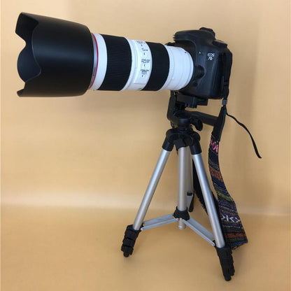 Black camera dummy with long telephoto lens mounted on tripod with strap