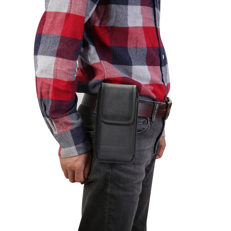 Vertical black waist bag with front flap and buckle strap on man’s jeans