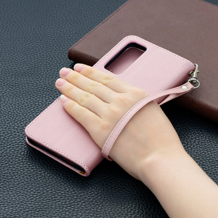 Rose gold textured flip phone wallet case held in hand, with wrist strap
