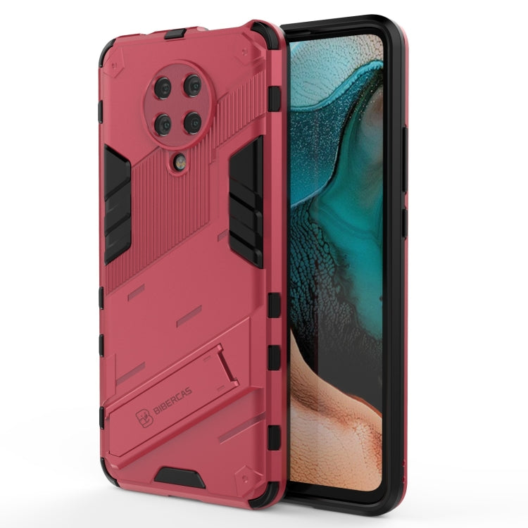 Rugged shockproof phone case with holder, pink-red back texture and black corner guards.