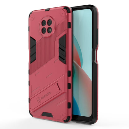 Rugged shockproof phone case with holder, rose-pink back with black inserts, front edge visible.