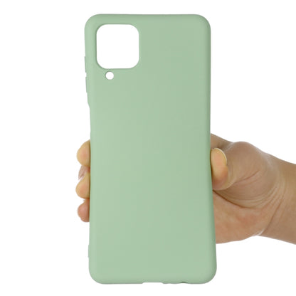 Green liquid silicone full-coverage phone case held in hand; camera and port openings.