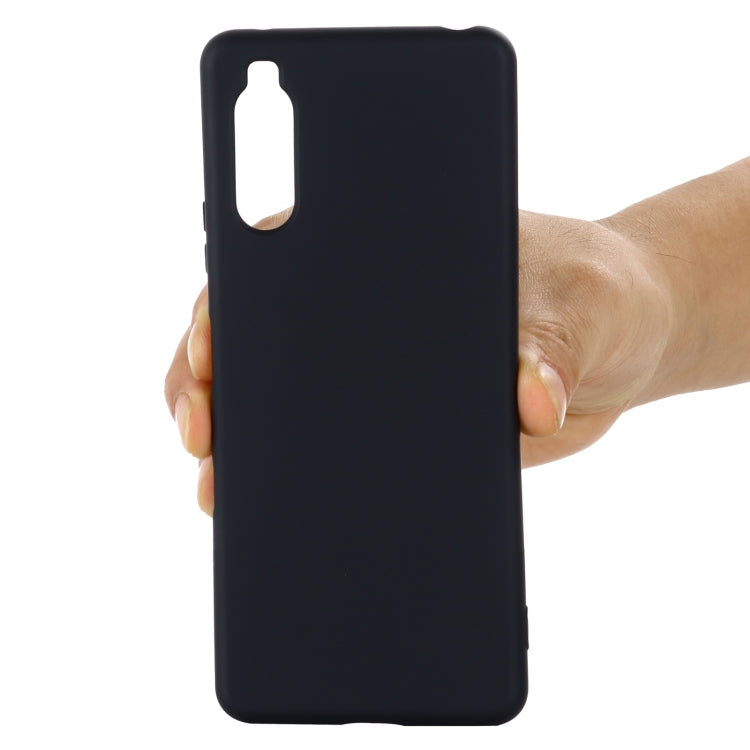 Black silicone phone case with camera cutout held in hand
