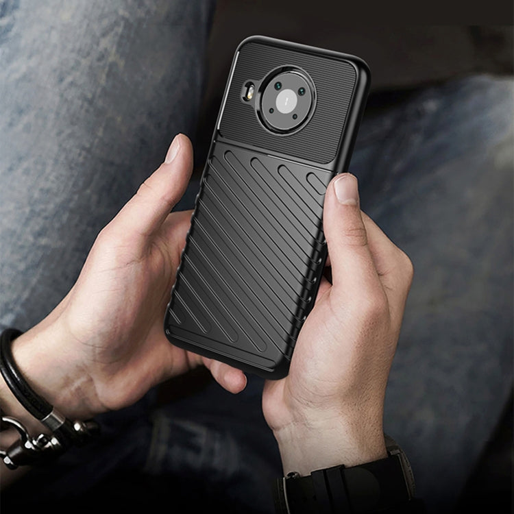 Black textured phone case held in hand with camera cutout