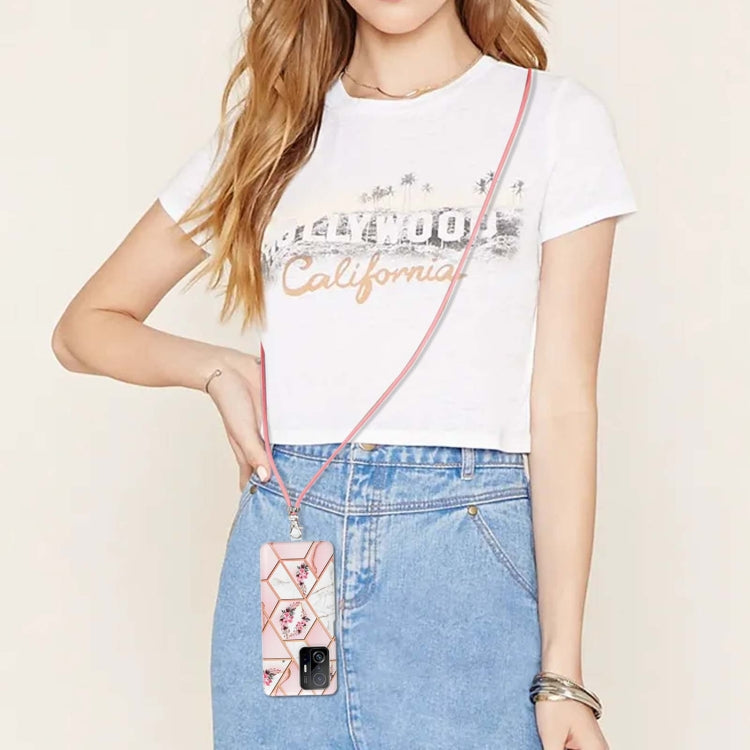Pink floral TPU phone case with lanyard hanging from jeans pocket