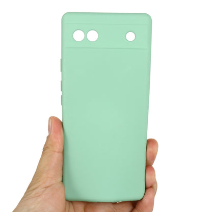 Mint green silicone phone case for Pixel 6a, back held in hand