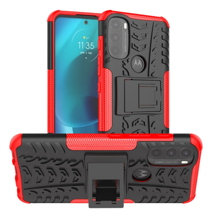 Red and black rugged phone case with tire tread texture, holder stand, and camera cutouts