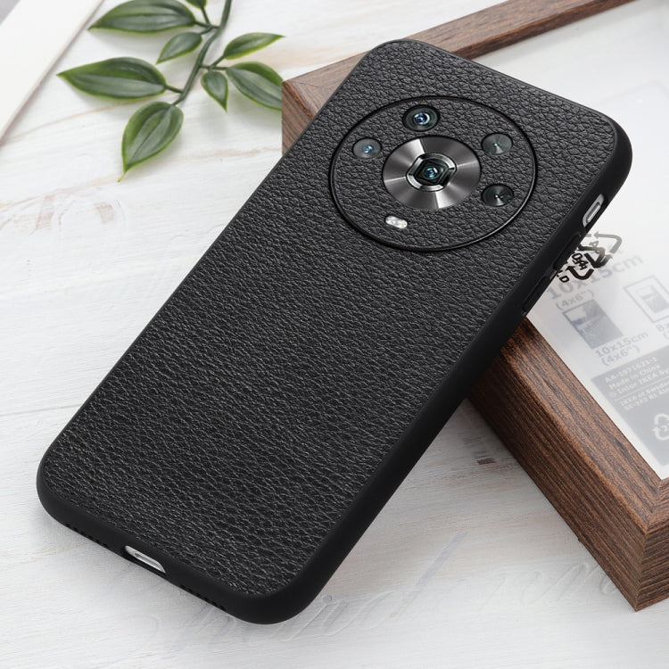 Black genuine leather phone case with litchi texture and circular camera cutout (angled).