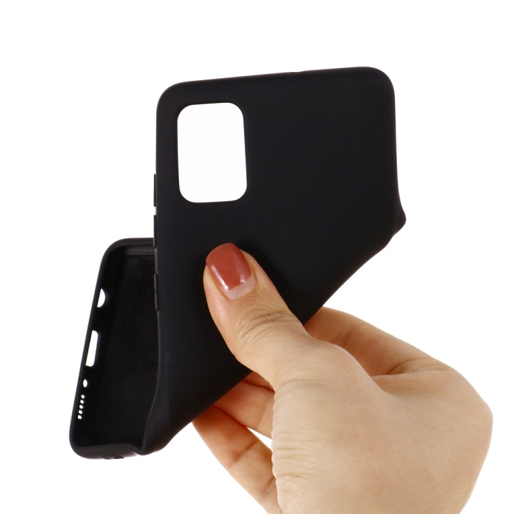 Liquid silicone phone case with camera cutout held by a hand (black).