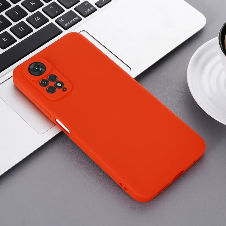 Red liquid silicone phone case on a desk near a laptop, angled view