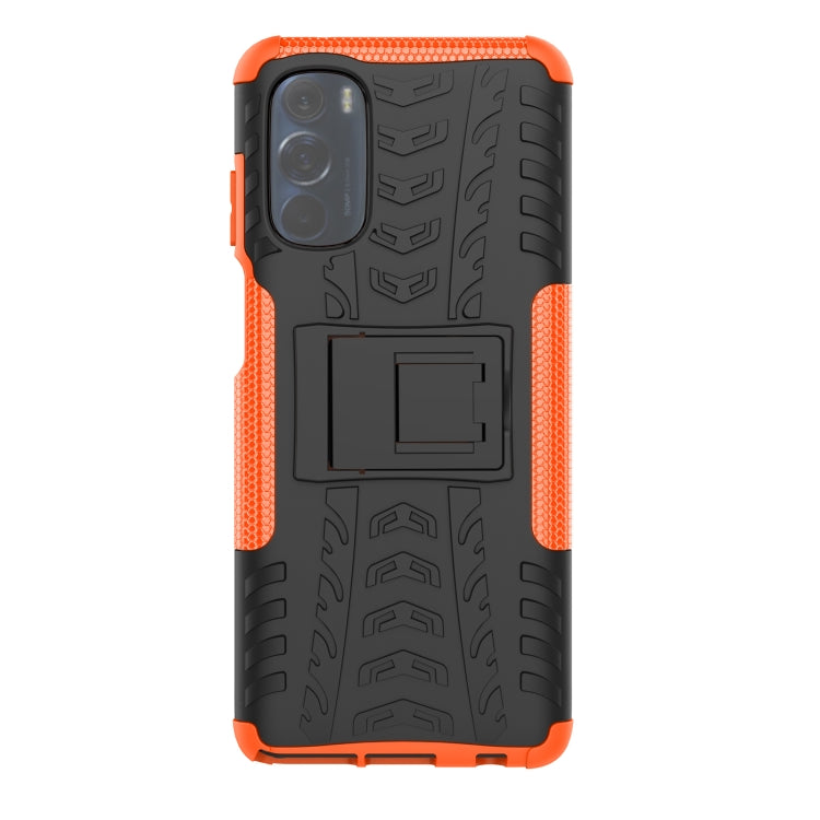 Tire-texture phone case with holder, orange accents and black back, camera opening visible.