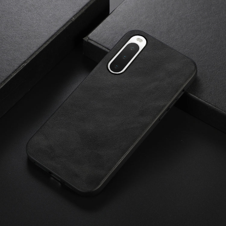 Black cowhide-textured PU phone case, angled view with camera cutout and ports