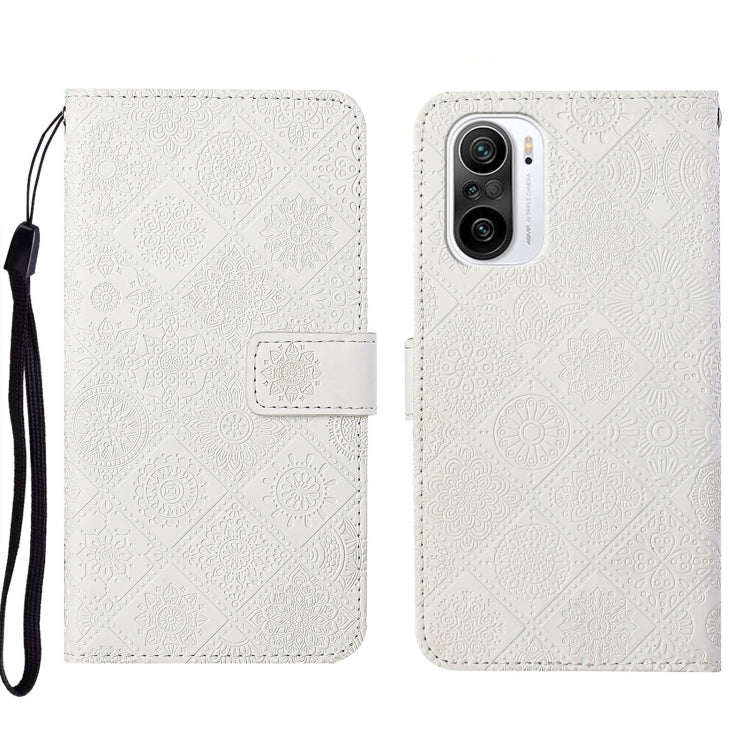 White embossed leather phone case wallet with flip cover and wrist strap.