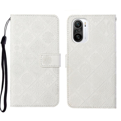 White embossed leather phone case wallet with flip cover and wrist strap.