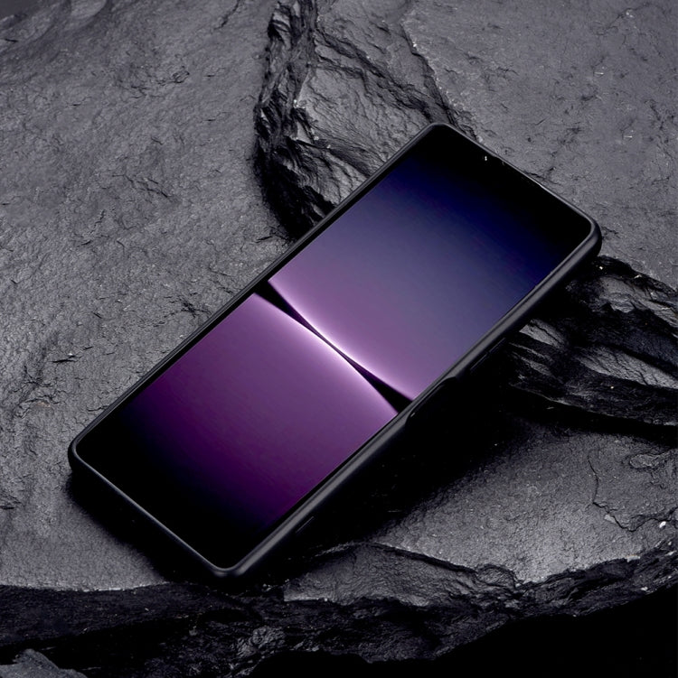 Black protective phone case with metal holder, phone lying diagonally on dark surface.