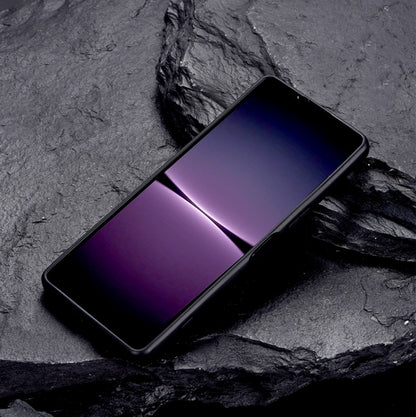 Black protective phone case with metal holder, phone lying diagonally on dark surface.