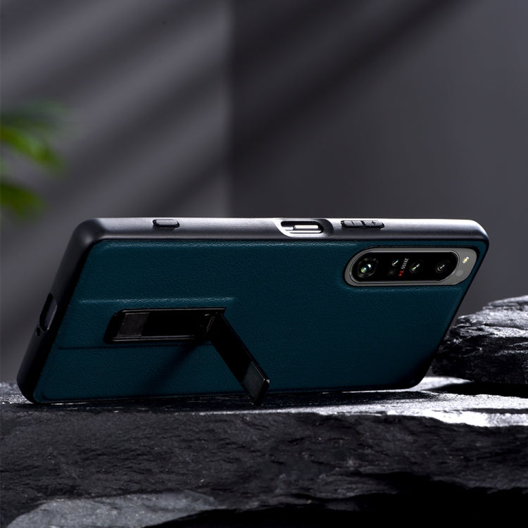 Teal leather-texture protective phone case with metal holder stand and camera cutout.