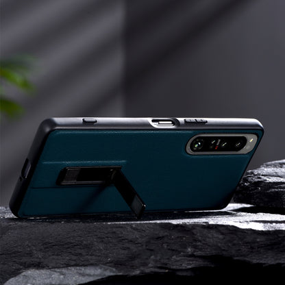 Teal leather-texture protective phone case with metal holder stand and camera cutout.