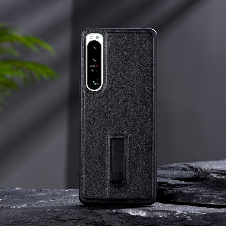 Black leather-texture protective phone case with metal holder slot and camera cutouts.