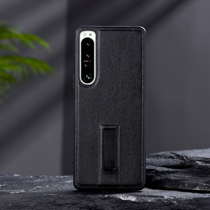 Black leather-texture protective phone case with metal holder slot and camera cutouts.