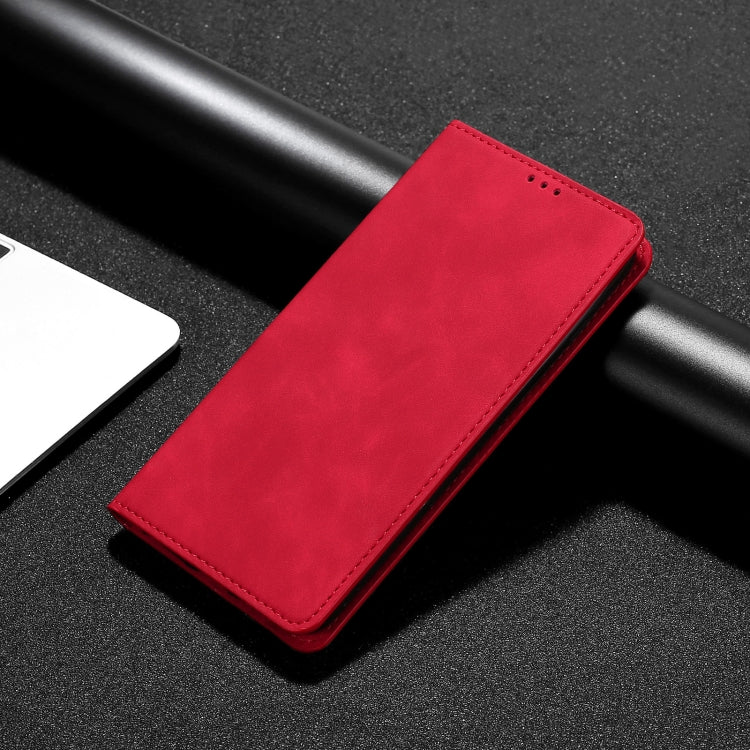 Red leather phone flip case with stitched edges, laid on black textured surface