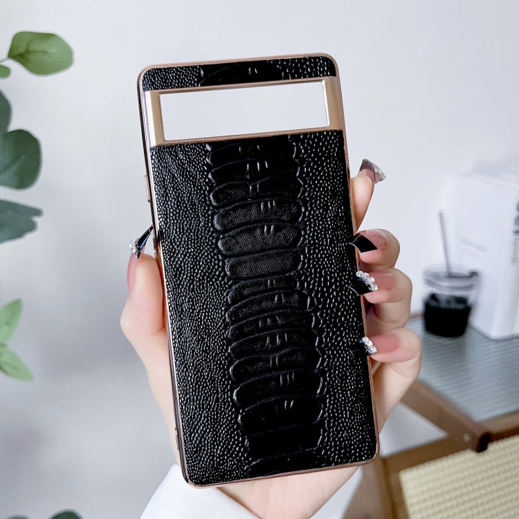 Black leather phone case with embossed alligator pattern, held in hand