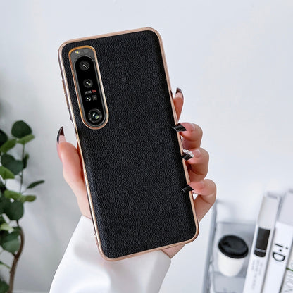 Black leather phone case with textured finish; worn in-hand view and camera cutout.