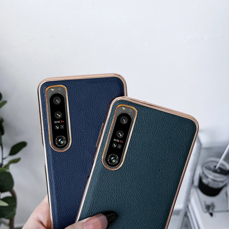 Pair of leather phone cases in black and dark green; camera cutouts visible.