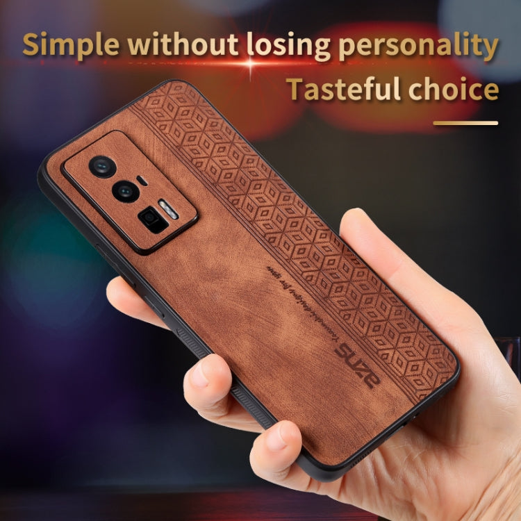 Brown phone case held in hand, embossed geometric border and camera cutout visible
