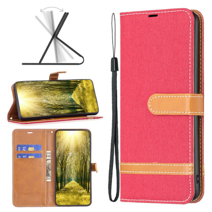 Red denim-texture leather phone case with tan wrist strap and stitched accents