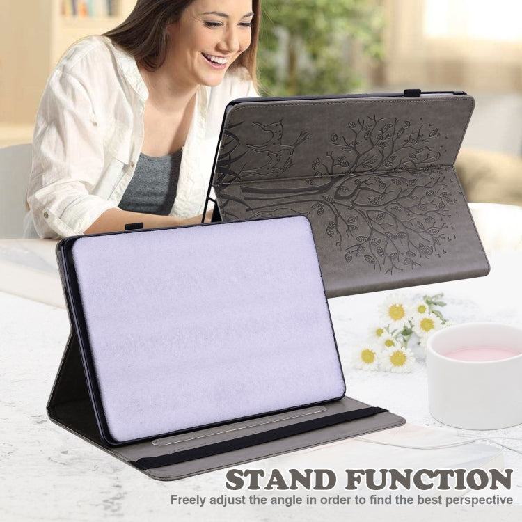 Grey embossed leather-style tablet case with tree and deer pattern, stand in use
