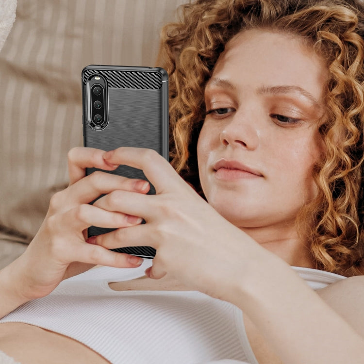 Black brushed texture TPU phone case with carbon fiber trim, shown in hand