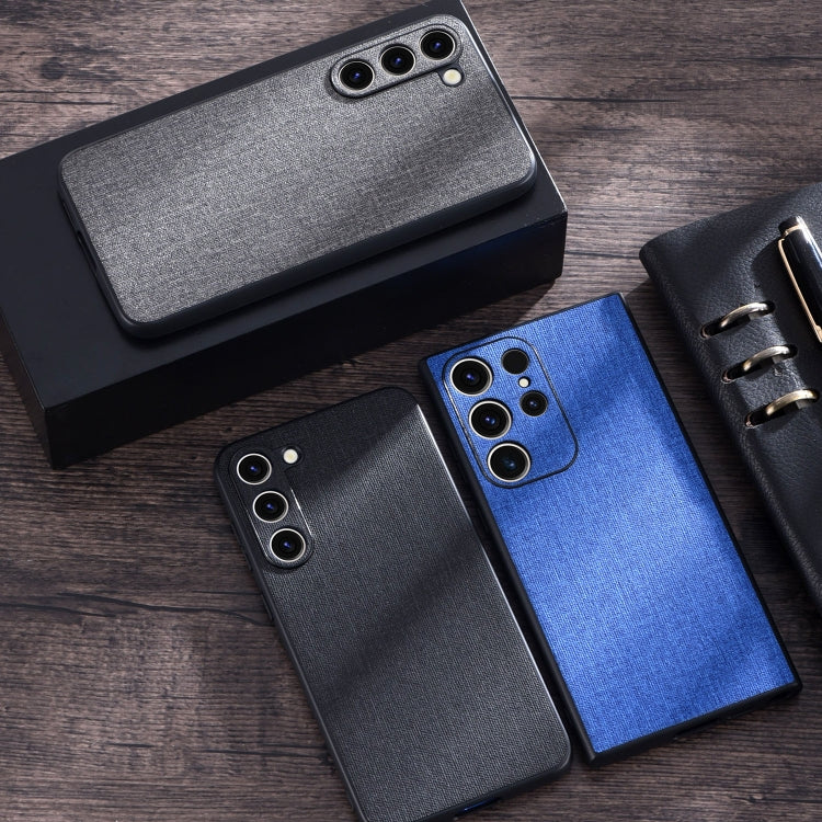 Cloth-texture phone cases in grey, blue, and black with camera cutouts