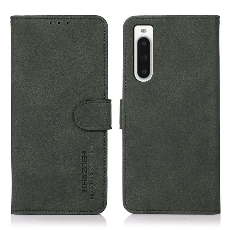 Matte green leather phone case with flip cover and holder strap; vertical camera cutout.