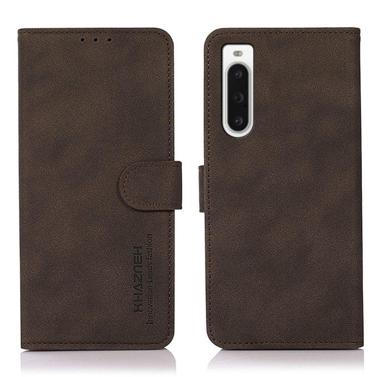 Matte brown leather phone case with flip cover and holder strap; vertical camera cutout.