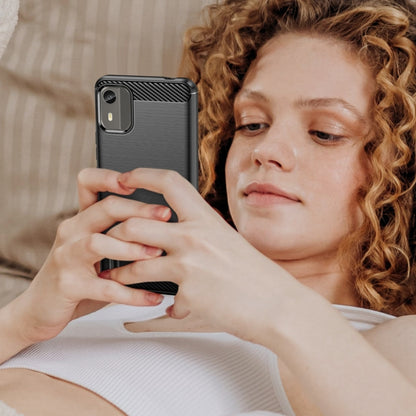 Brushed carbon fiber TPU phone case on phone, black, shown being held by a person