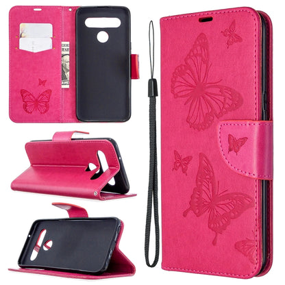 Pink leather-style phone wallet case with embossed butterflies, card slots, and wrist strap