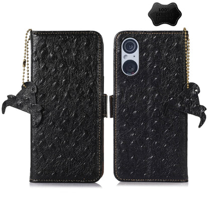 Black ostrich leather phone wallet case with dual camera cutout, animal charm and strap