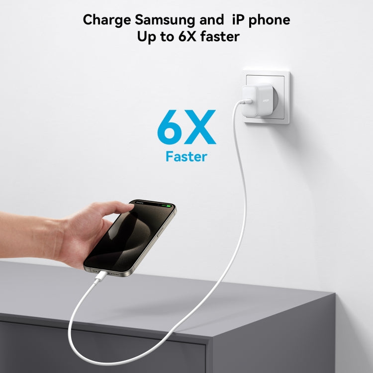 White USB-C charger in EU wall outlet powering a smartphone on desk