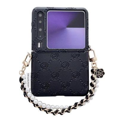 Black embossed phone case with rose pattern, side buckle, and chain wrist strap