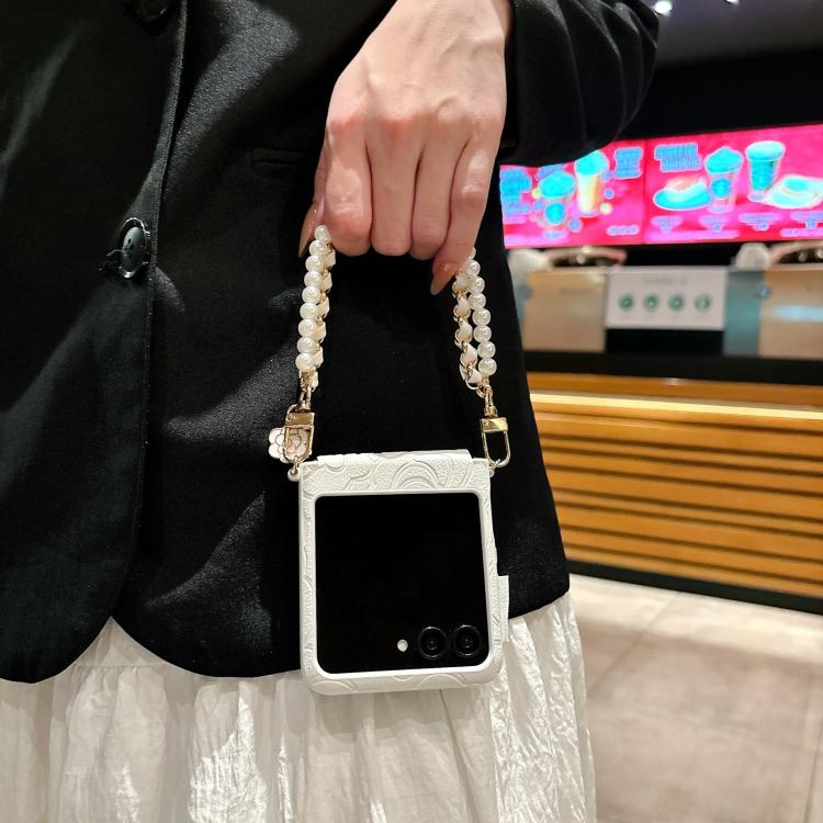 White embossed camellia phone case with side buckle and pearl wristlet strap.