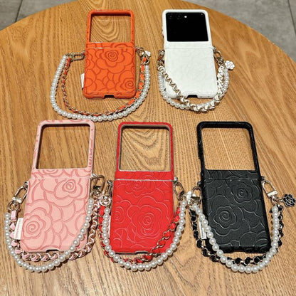 Assorted camellia embossed phone cases with side buckle and pearl bracelet straps.