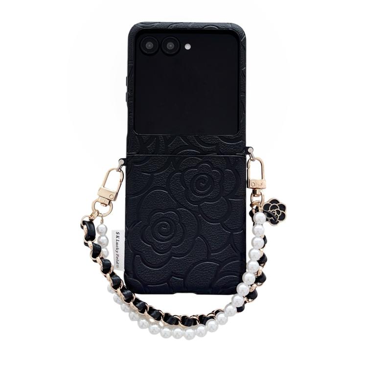 Black embossed camellia phone case with side buckle and pearl bracelet strap.