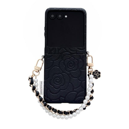 Black embossed camellia phone case with side buckle and pearl bracelet strap.