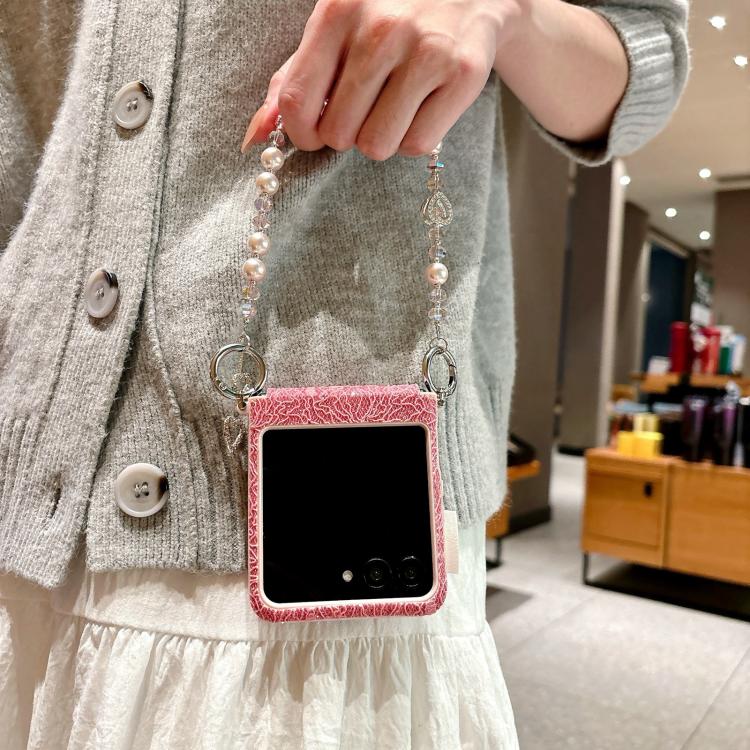 Pink lace-embossed phone case worn with beaded wrist strap and metal hooks