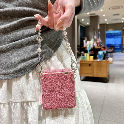 Pink lace-embossed phone case with metal hooks and beaded wrist strap, heart charms
